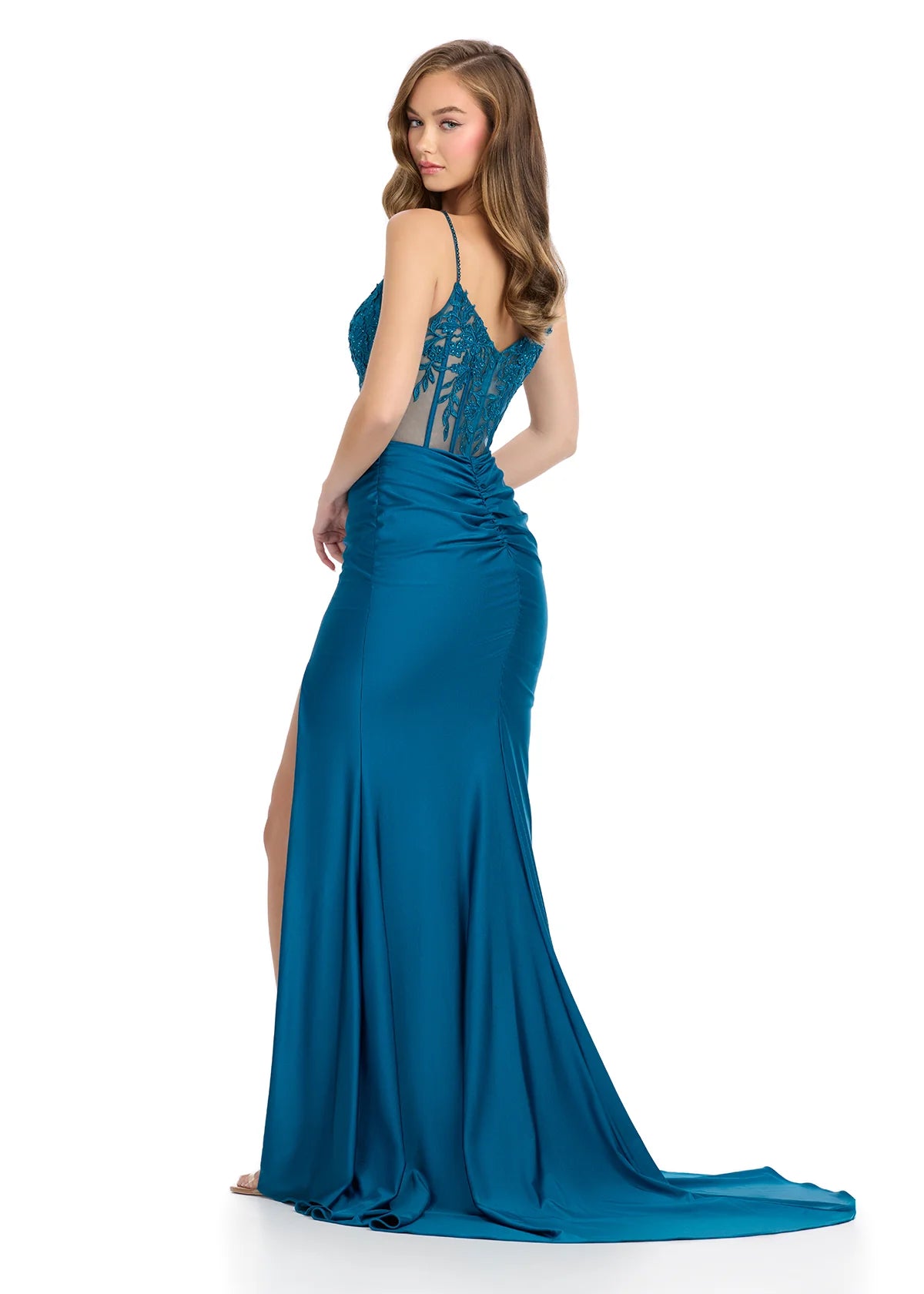 Back view of a teal evening gown featuring a sheer illusion bodice with floral lace appliqués, thin spaghetti straps, a thigh-high slit, and a flowing floor-length skirt.