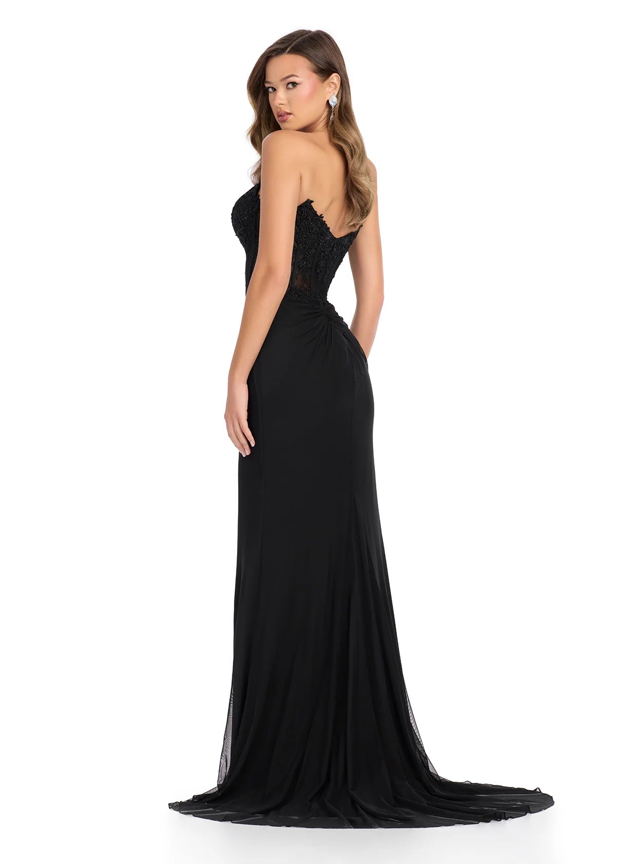 Back view - Elegant black floor-length gown featuring a strapless sweetheart neckline, sheer lace bodice, ruched detailing, cascading ruffle accents, a thigh-high slit, and a flowing train for a dramatic and sophisticated look.