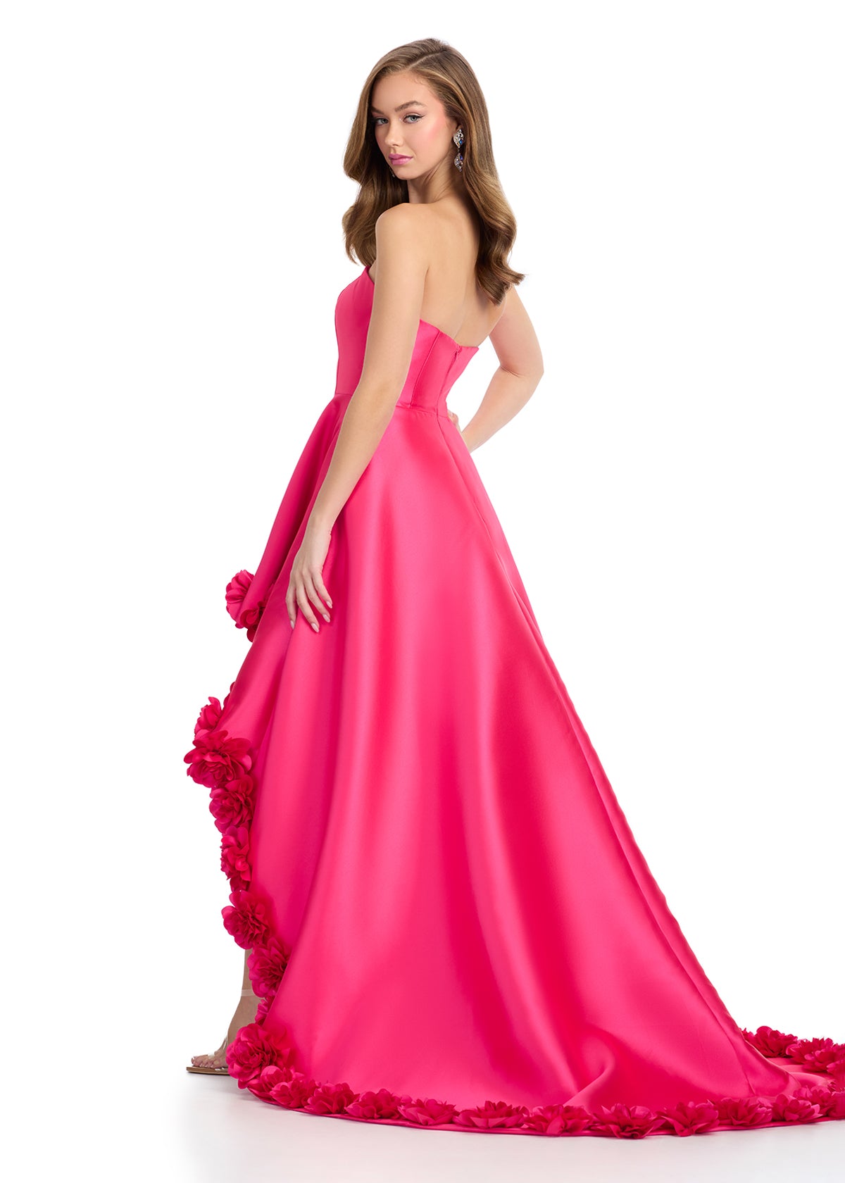 Back view - Fuchsia high-low gown with a strapless bodice, satin finish, and dramatic floral appliqué detailing along the hem, creating a bold and romantic statement.