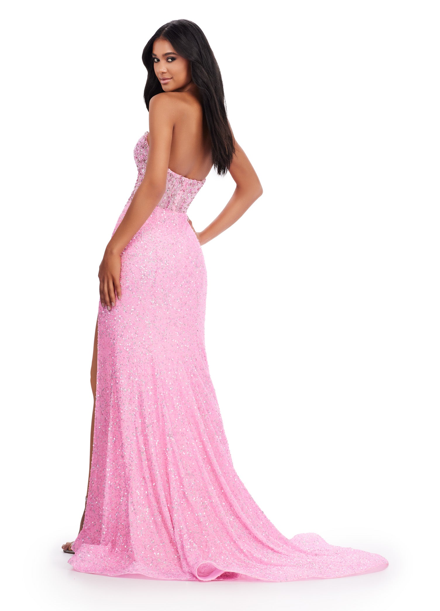 Glittering pink evening gown with a strapless sweetheart neckline, fitted sheer bodice, and high thigh slit. The dress features delicate beading and sparkles throughout, paired with a flowing floor-length skirt.