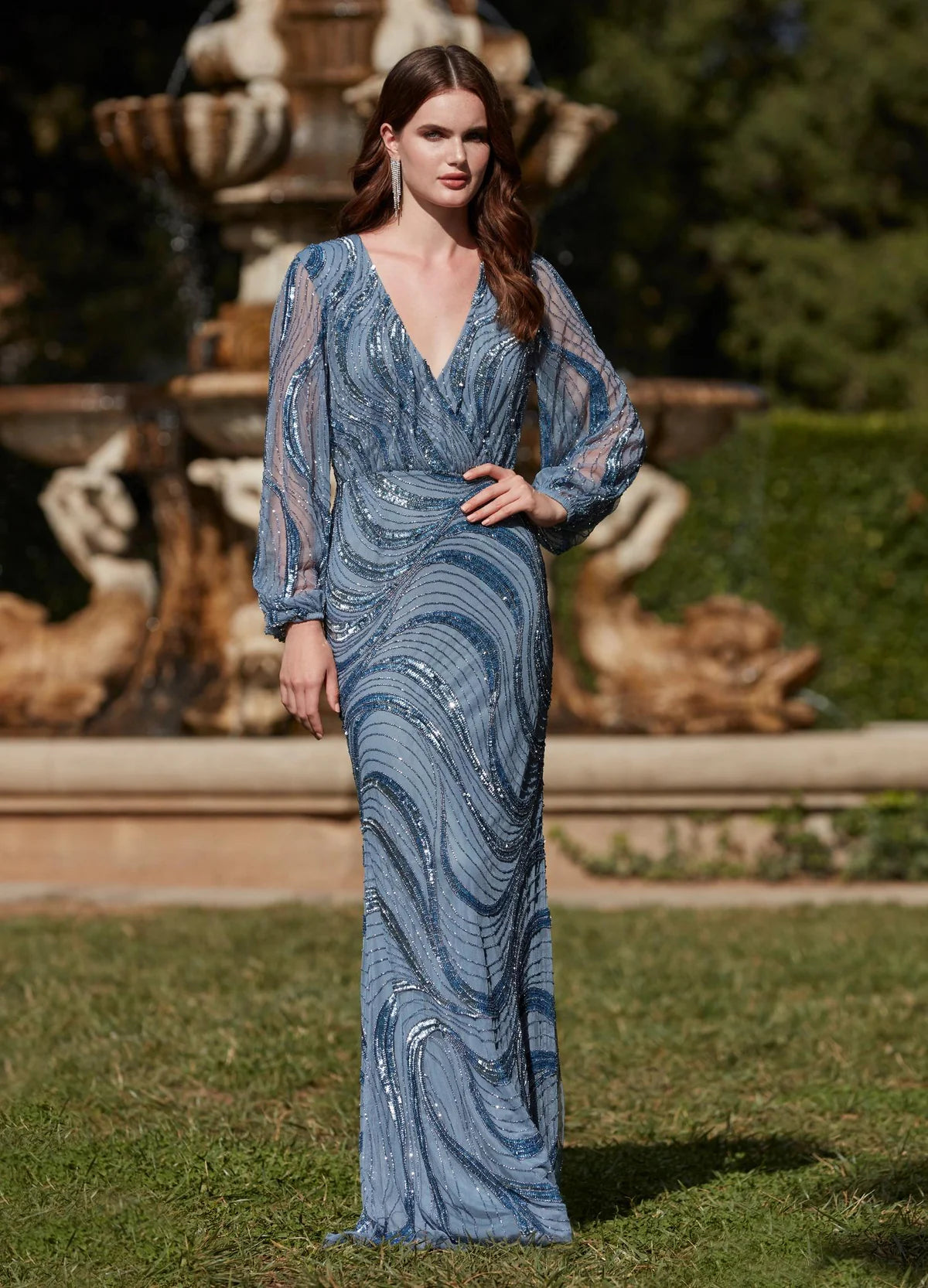 Video - Exquisite floor-length gown featuring a plunging neckline, long sheer sleeves, intricate sequin patterns, and a fitted silhouette for a glamorous and elegant look.