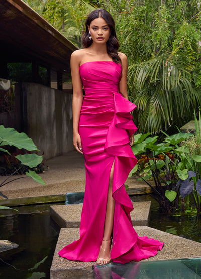 Video - Fuchsia strapless evening gown featuring a structured bodice, asymmetrical ruffle detailing cascading along the skirt, and a thigh-high slit for a modern and sophisticated silhouette.